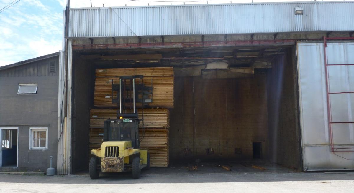A forklift carrying a pallet of fried lumber out of a drying kiln.
