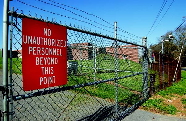 security fence around buildings with 'no unauthorized personnel' sign