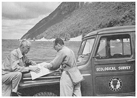 Charles Doll and John Dennis examining a map with Lake Willoughby and Mount Pisgah in the background
