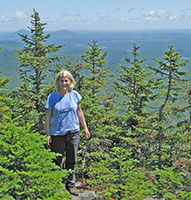 Marjorie Gale standing among trees atop a mountain