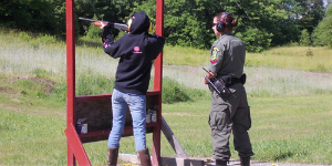 a teen aims a rifle under hunter safety instructor supervision at Buck Lake Shooting Range