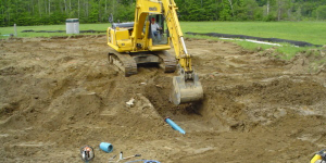 an excavator places backfill over a new pipe