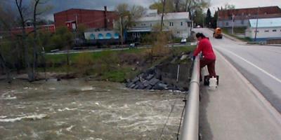 Person sampling a tributary of Lake Champlain from a bridge