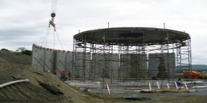 a crane hoist sets precast concrete panels for a new water storage tank
