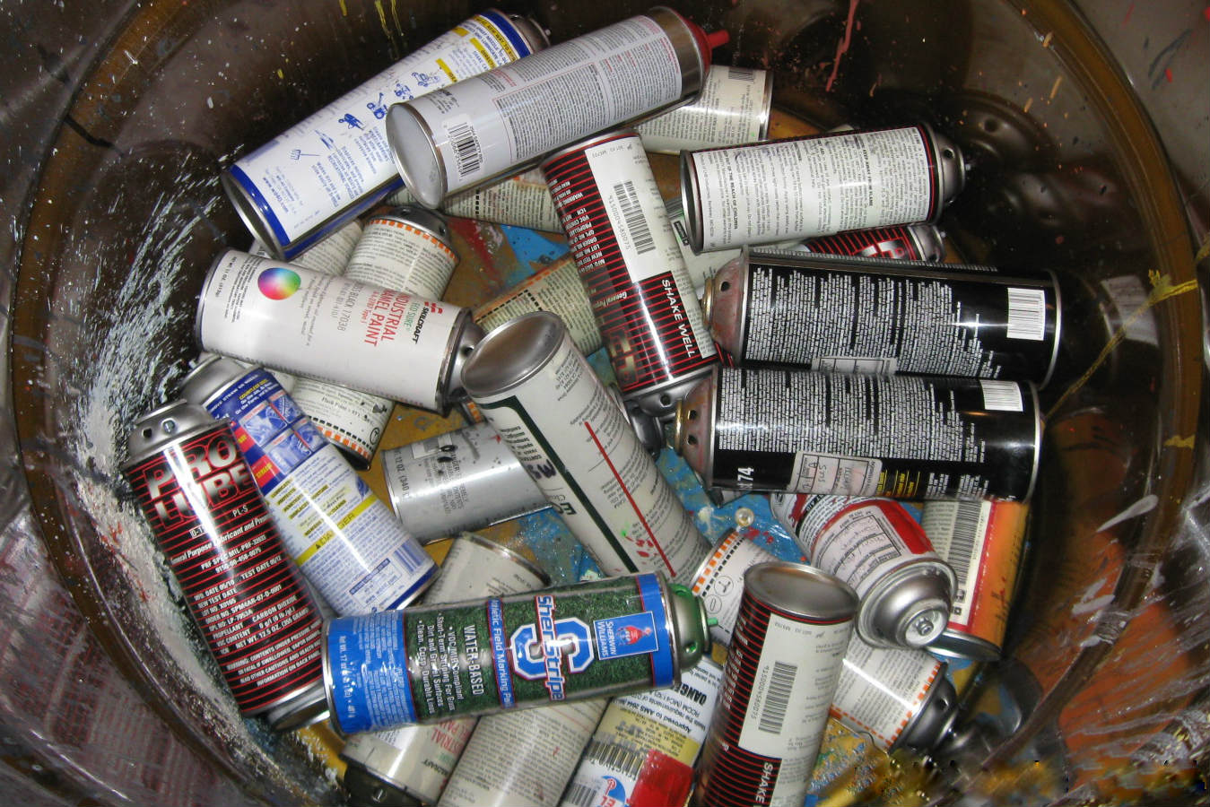 Waste aerosol cans in a drum for disposal