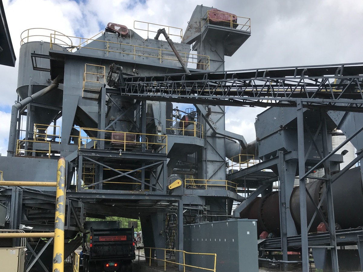 A hot mix asphalt facility with a dump truck receiving asphalt mixture