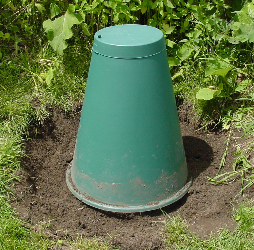 A green cone digester dug into the ground