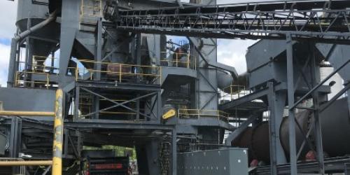 A hot mix asphalt facility pouring asphalt material into a dump truck