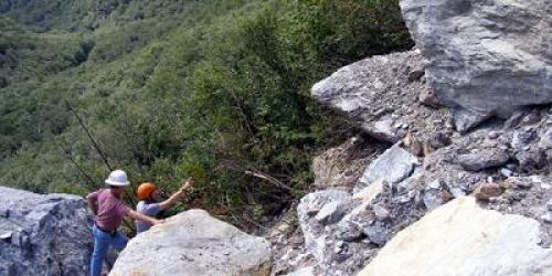 Two people in hard hats looking at a rockfall in Smugglers Notch