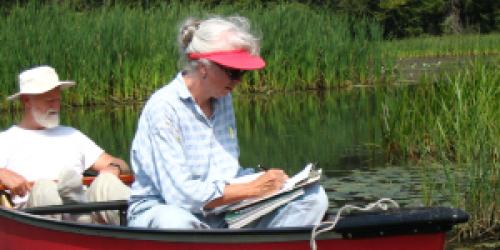 Two Vermont Invasive Patrollers in a canoe recording data.