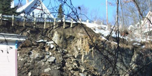 View from street looking up at a crumbled hillside destroyed by rockfall