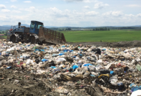 Photo of an active landfill, with a piece of heavy equipment moving trash