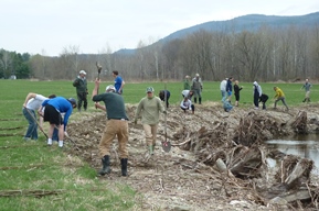 A dozen or so people working on a streambank restoration.