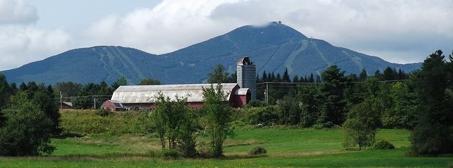 Image of mountains, red barn, and agriculture field