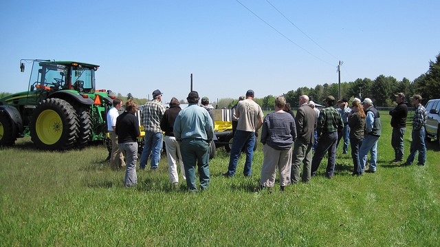 People standing around a tractor in an agricultural field
