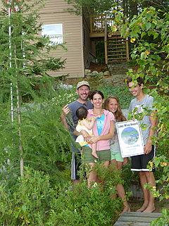 A family in front of their house, where the property design earned them the Lake Wise Award