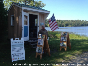 Greeter stand at Salem Lake, with greeter standing outside by informational sandwich boards