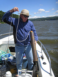 man pulling water sample from lake onto boat