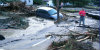 Washed out pavement, trees in road, and flooded car