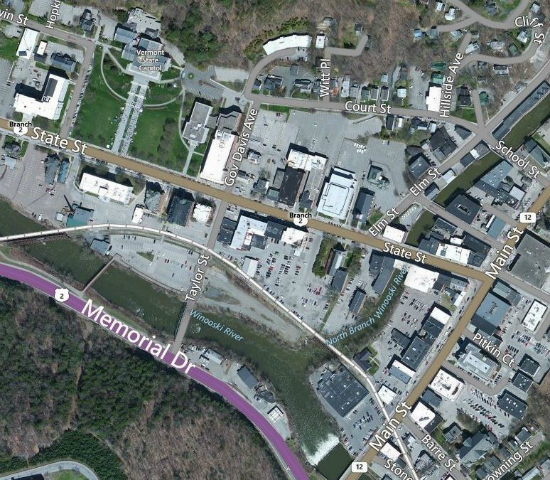 Aerial view of downtown Montpelier.  In the top left, the State House building is seen.  In the lower left, a small part of National Life drive is seen. Towards the right of the photo, the North Branch of the Winooski River is seen flowing from near the top of the image into the Winooski River which flow from right to left near the bottom of the image.