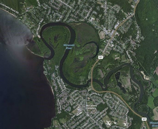 Aerial view of the mouth of the Winooski River.  The river is seen flowing from the right of the photo to the left.  The left third of the image shows Lake Champlain which looks like a large black area.