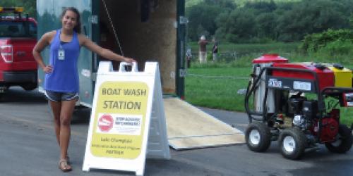 Boat Wash Technician standing beside sign and Decon unit.