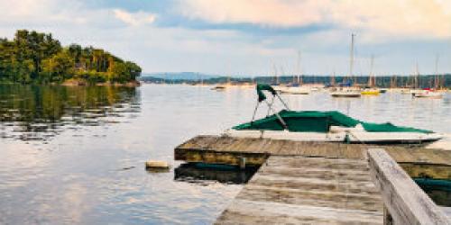 A dock and boat as seen from someone's lake front house. 